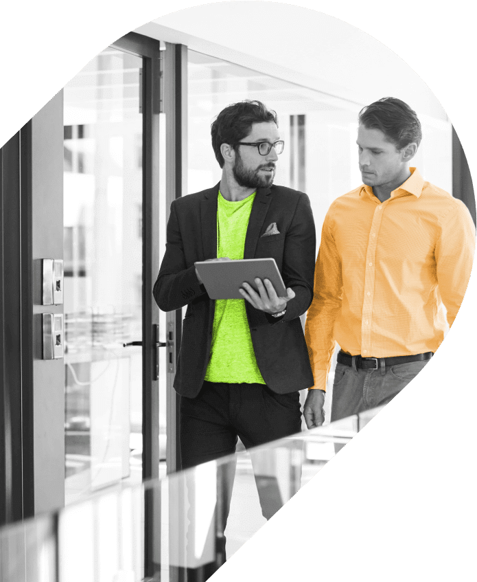 Two men walking in an office looking at tablet